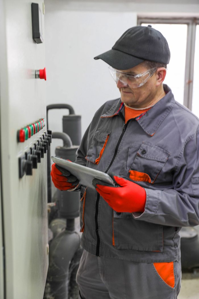 Invoice financing for small business: a technician checking readings on a tablet beside a control panel